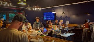 Regulars around the wraparound wooden bar at Hava Kava Port St. Lucie, under pendant lights against navy walls